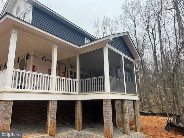 view of home's exterior with gravel driveway and a sunroom