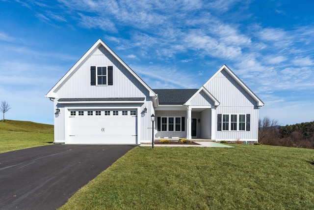 modern farmhouse with driveway, a shingled roof, board and batten siding, and a front yard