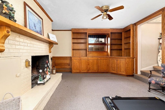 living room featuring a fireplace, ceiling fan, crown molding, and light colored carpet