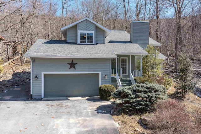 view of front of home with roof with shingles, a chimney, covered porch, an attached garage, and driveway