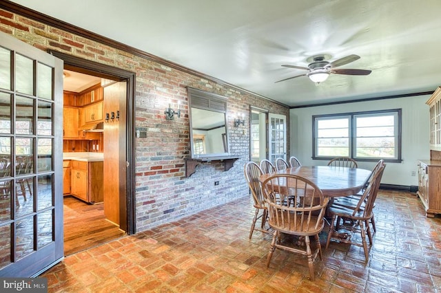 dining space with brick wall, a ceiling fan, crown molding, and brick floor