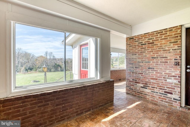 unfurnished room with brick floor and brick wall