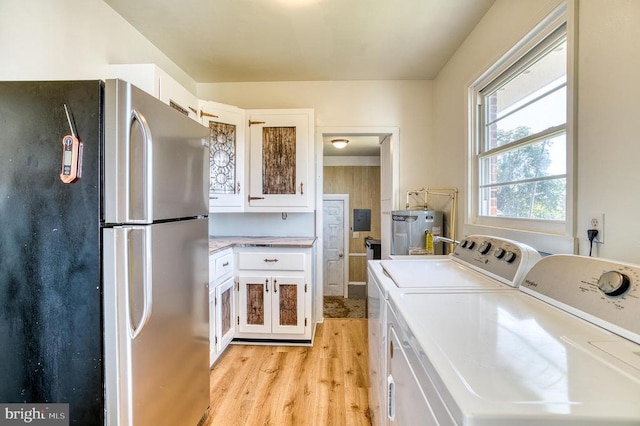 washroom featuring water heater, laundry area, washer and dryer, and light wood finished floors