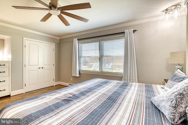 bedroom with ornamental molding, a ceiling fan, wood finished floors, a closet, and baseboards