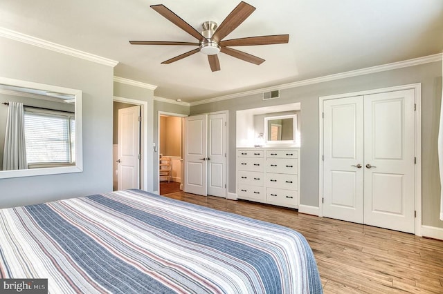 unfurnished bedroom with visible vents, crown molding, multiple closets, light wood-style floors, and a ceiling fan