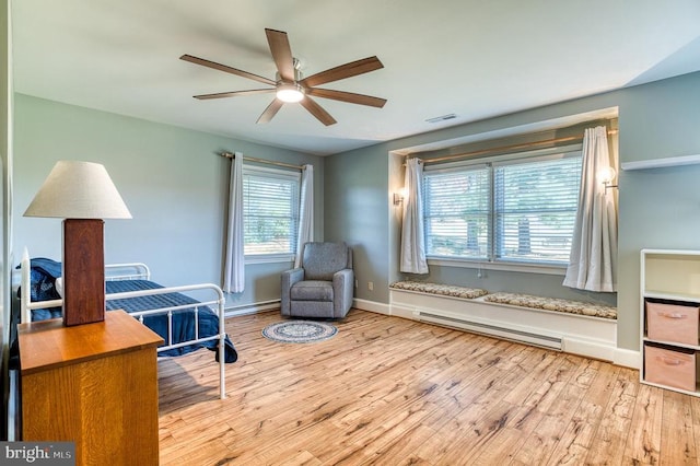 bedroom featuring visible vents, a baseboard heating unit, baseboards, wood finished floors, and a ceiling fan