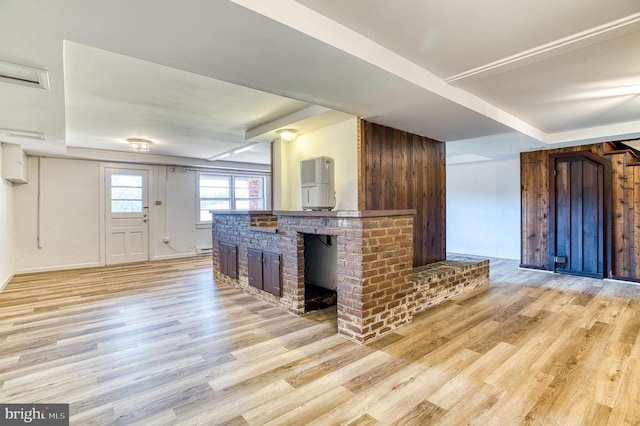 kitchen with a tray ceiling, light wood-style floors, a fireplace, and a baseboard radiator