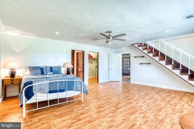 bedroom with baseboards, wood finished floors, visible vents, and a textured ceiling