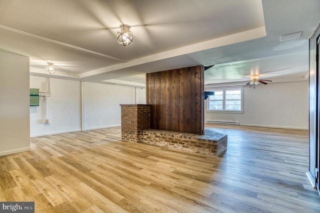 unfurnished living room featuring a baseboard heating unit, light wood-style floors, and baseboards