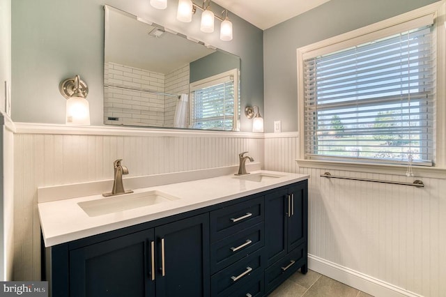 bathroom featuring plenty of natural light, a wainscoted wall, and a sink