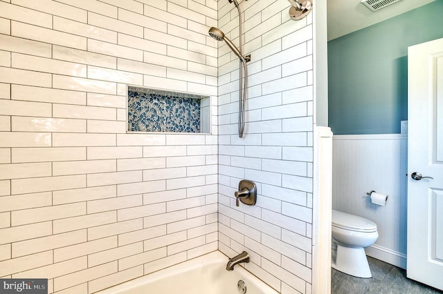 bathroom with washtub / shower combination, toilet, visible vents, and wainscoting