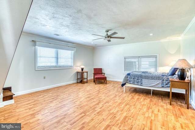 bedroom featuring visible vents, a textured ceiling, wood finished floors, crown molding, and baseboards