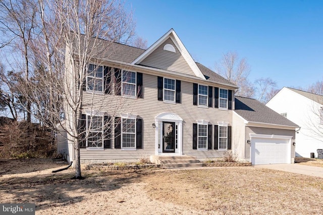 colonial inspired home featuring a garage, driveway, and a shingled roof