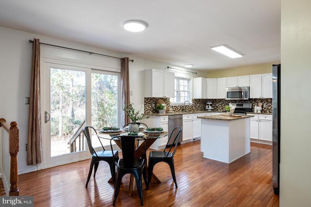 kitchen featuring stainless steel appliances, a kitchen island, tasteful backsplash, and white cabinets