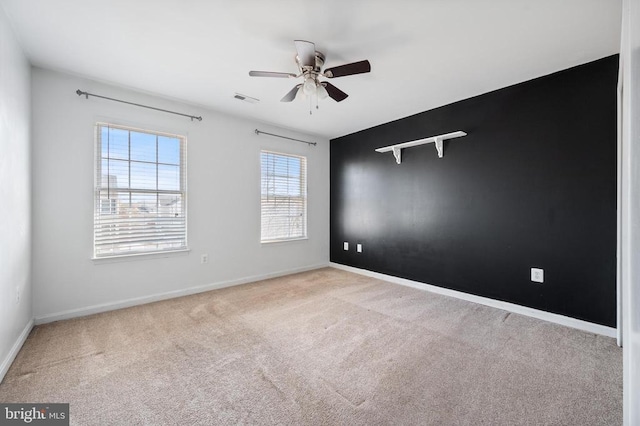 carpeted empty room featuring visible vents, a ceiling fan, and baseboards