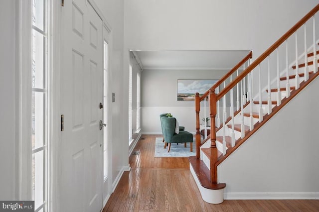 foyer entrance with stairs, wood finished floors, and baseboards