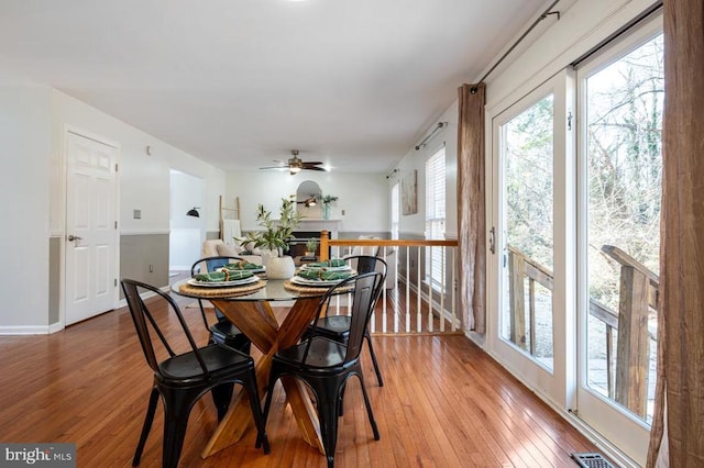 dining area with visible vents, ceiling fan, a fireplace, and light wood finished floors