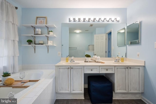 bathroom with a garden tub, double vanity, visible vents, and a sink