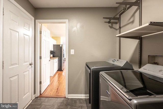 clothes washing area with washer and dryer, laundry area, parquet flooring, and baseboards