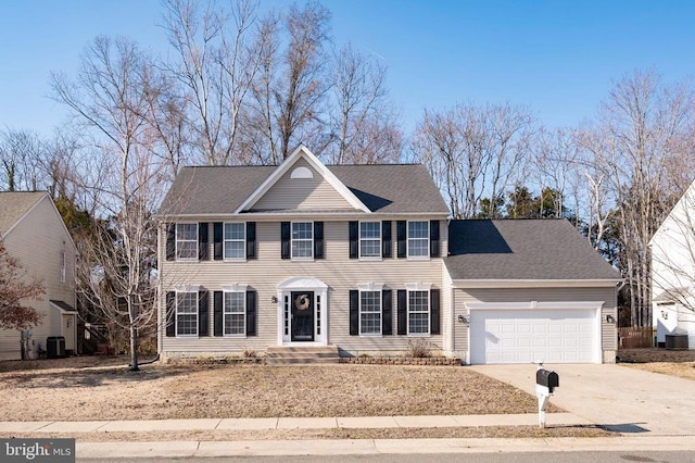 colonial house featuring driveway, an attached garage, central AC, and roof with shingles