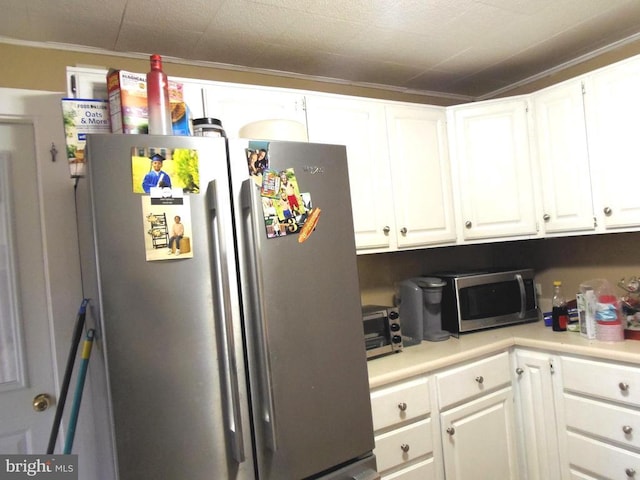 kitchen with stainless steel appliances, ornamental molding, light countertops, and white cabinetry