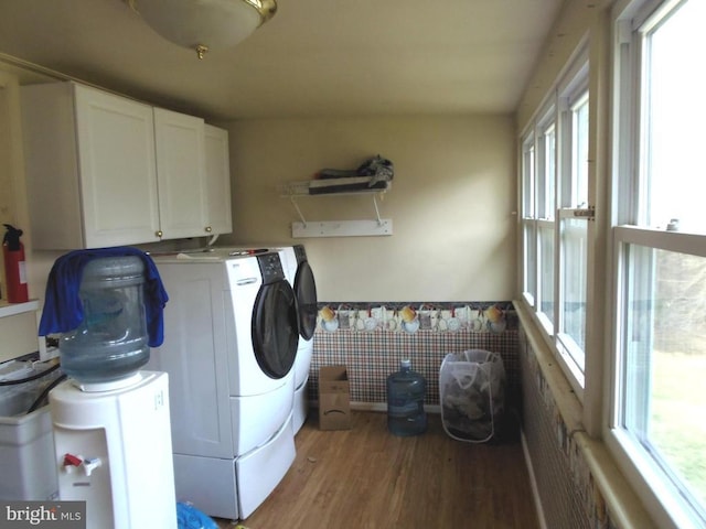 clothes washing area featuring a wainscoted wall, cabinet space, separate washer and dryer, and wood finished floors