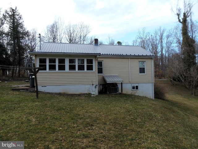 back of house with a yard, a chimney, and metal roof