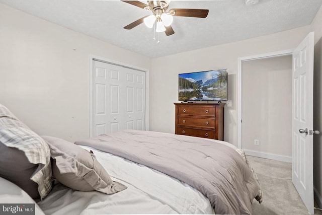 bedroom with a ceiling fan, a closet, light colored carpet, and baseboards