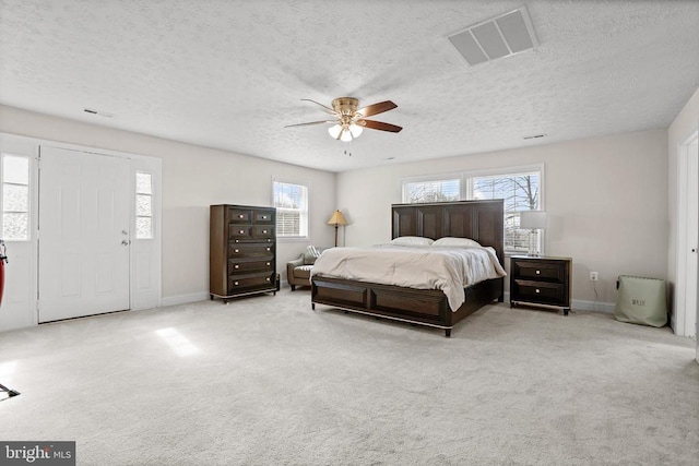 bedroom with visible vents, a textured ceiling, carpet flooring, and multiple windows