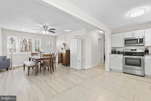 kitchen with baseboards, white cabinets, appliances with stainless steel finishes, a textured ceiling, and light wood-type flooring