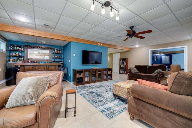 living room featuring bar, light tile patterned floors, a paneled ceiling, and ceiling fan