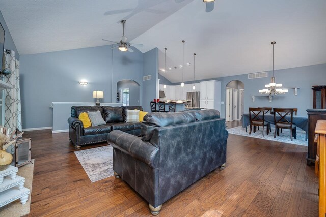 living room featuring ceiling fan with notable chandelier, dark wood-type flooring, and high vaulted ceiling