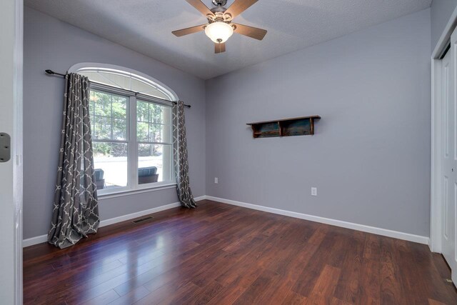 unfurnished room with ceiling fan, dark wood-type flooring, and a textured ceiling