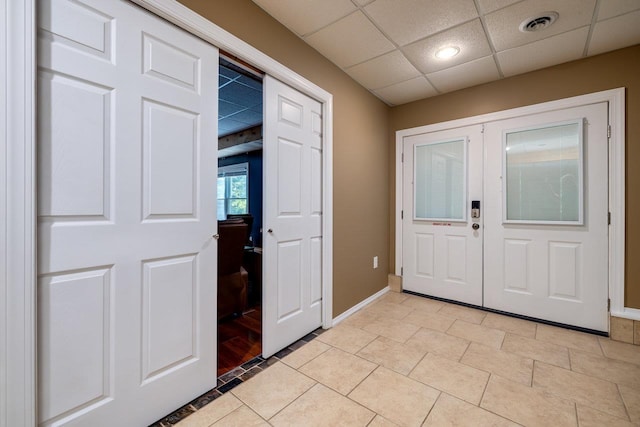 entrance foyer with light tile patterned flooring, a paneled ceiling, and french doors