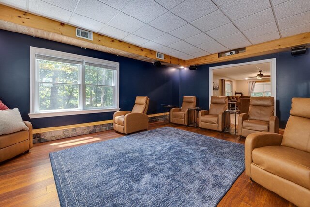 living area featuring a drop ceiling and wood-type flooring