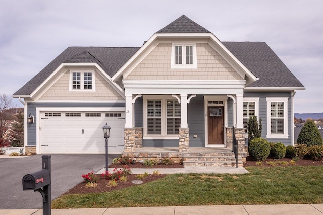 craftsman-style home with a garage, covered porch, and a front lawn