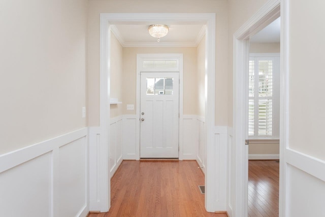 doorway with ornamental molding, a healthy amount of sunlight, and light hardwood / wood-style flooring