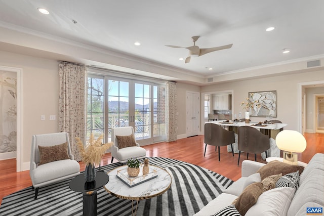 living area featuring french doors, crown molding, and light wood-style floors