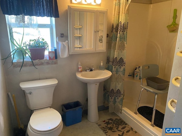 full bath with toilet, a stall shower, and a sink