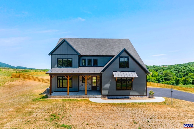 modern inspired farmhouse featuring roof with shingles, board and batten siding, a front lawn, and fence