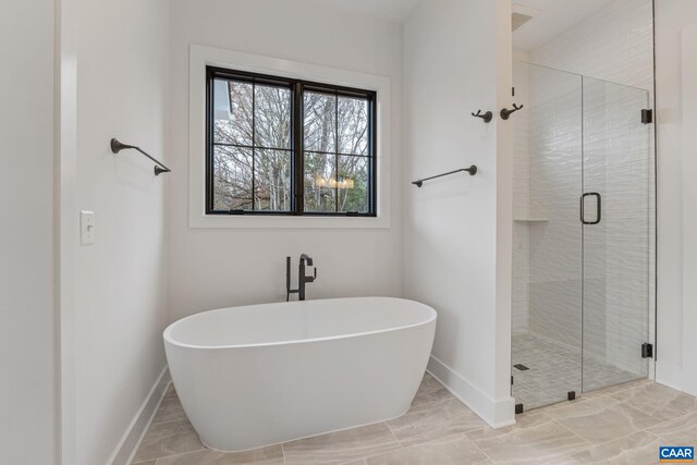 full bath featuring a soaking tub, a shower stall, and baseboards