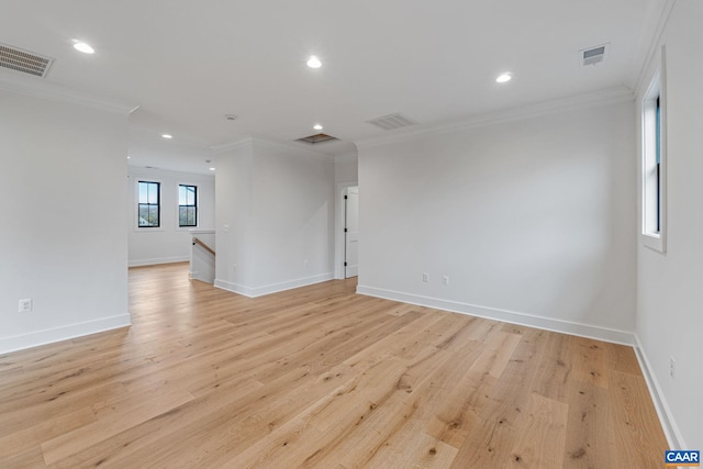 empty room featuring light wood-type flooring, visible vents, and ornamental molding