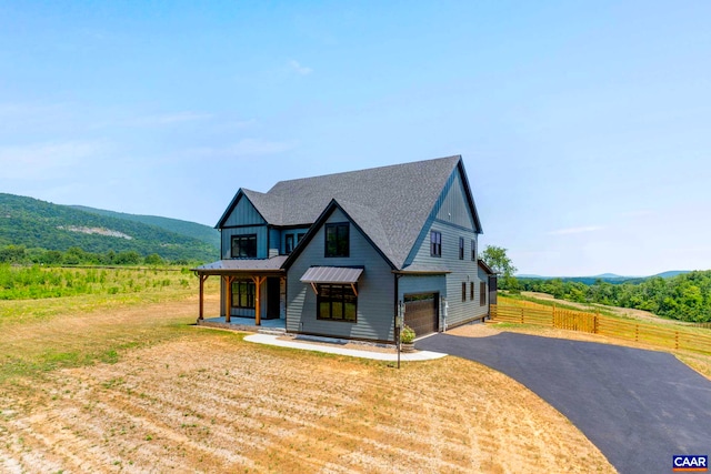 view of front of home with driveway, fence, a mountain view, an attached garage, and metal roof