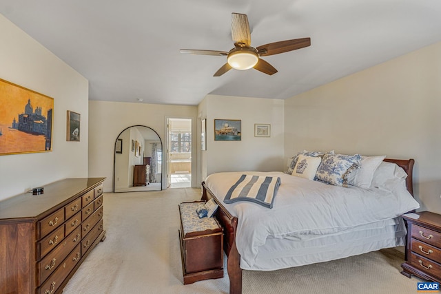 bedroom with a ceiling fan, light colored carpet, and connected bathroom