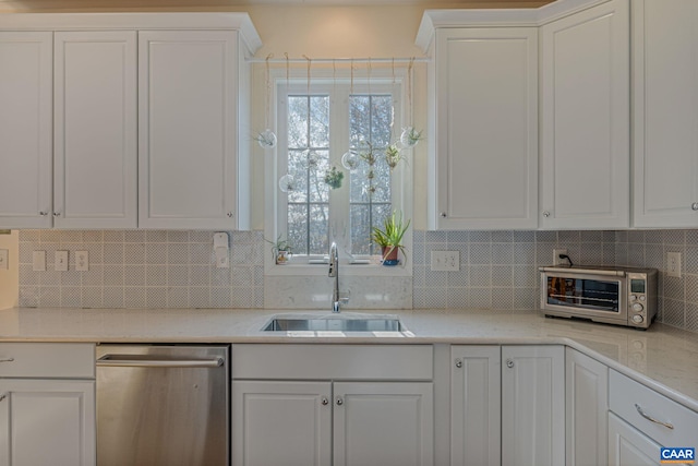 kitchen featuring a sink, light countertops, white cabinets, stainless steel dishwasher, and backsplash