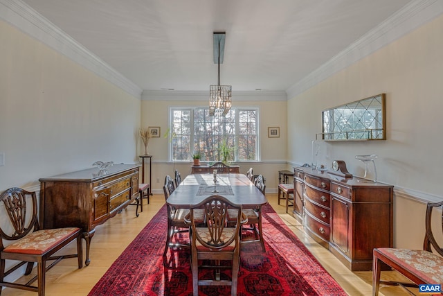 dining area featuring light wood-style flooring, a notable chandelier, baseboards, and ornamental molding