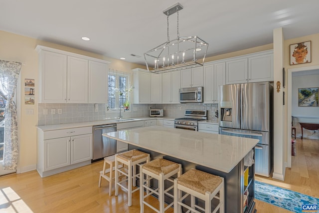 kitchen featuring tasteful backsplash, light wood-style flooring, appliances with stainless steel finishes, and a sink