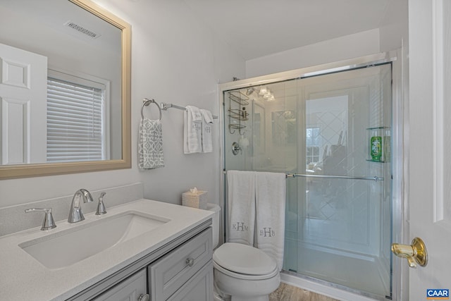 bathroom with vanity, toilet, visible vents, and a stall shower