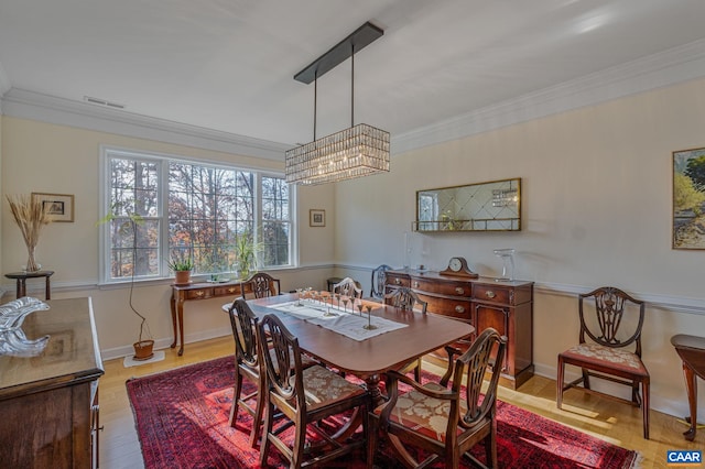 dining room with visible vents, wood finished floors, and ornamental molding