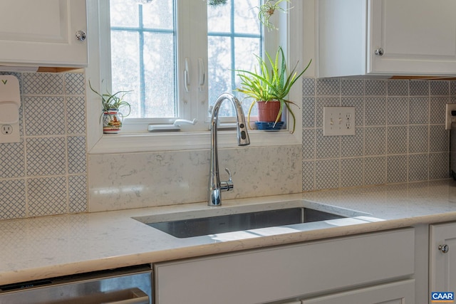 interior details with a sink, decorative backsplash, dishwasher, and white cabinets